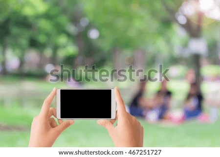 woman use mobile phone and blurred image of people in the park
