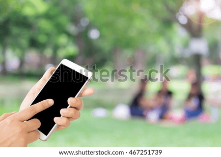 woman use mobile phone and blurred image of people in the park