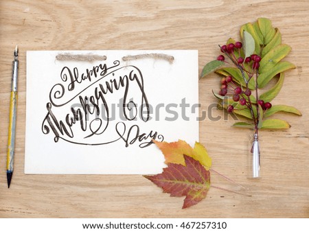 Kraft notepad with ink pen, colorful leaves and red berries. Happy thanksgiving day lettering.