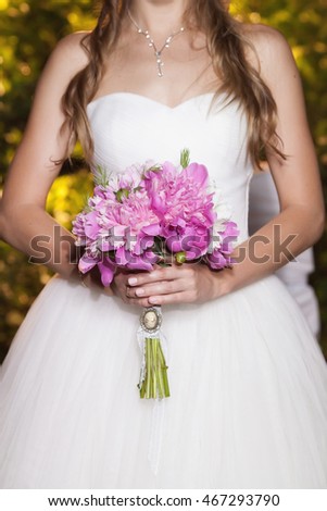 Beautiful pink peony wedding bouquet in bride's hands, closeup, selective focus. Marriage concept