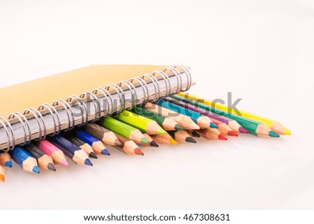 color pencils of various colors near a notebook on a white background