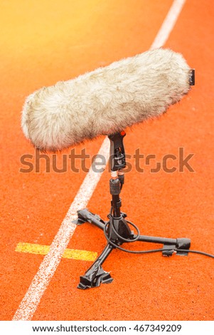 Directional microphone boom with windshield at a football stadium.

