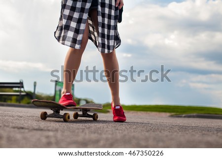 Beautiful woman with tattoo  in pink shoes is skating on an old skate on the background of blue sky.