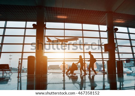 people in airport, silhouette of young family with baby traveling by plane, vacations