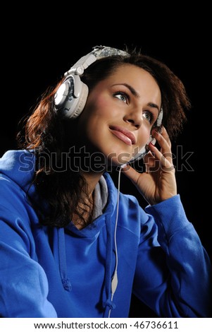 Portrait of the young woman listening to music on a black background