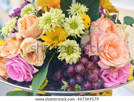 Flower composition with grapes, roses and gerberas.