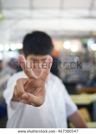 The boy show two finger sign to fighting and success focus on finger shallow with depth of field