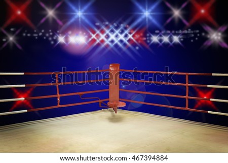 A dramatic view of the red corner of a regular boxing ring surrounded by ropes spotlit by a spotlight on an isolated dark background