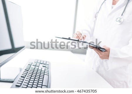 Close-up view of female doctor hands filling patient registration form. Healthcare and medical concept