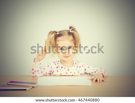 Little girl draws at table pencils. Preschool education.