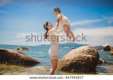 Lifestyle portrait mom and daughter in happines at the outside in the meadow.Happy loving family. 
Mother and child girl playing, kissing and hugging.Asian mother and daughter walking on the beach.