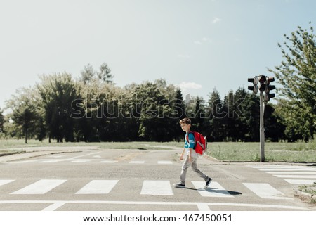 Schoolboy crossing road on way to school Royalty-Free Stock Photo #467450051