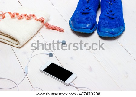 Sneakers, earphones and phone on wooden background.