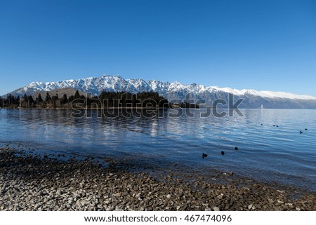 A winter view of The Remarkables with snow topped peaks behind the Queenstown golf course, from the side of Lake Wakatipu in Queenstown, New Zealand.