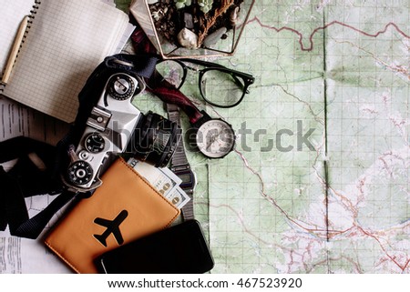 wanderlust and adventure concept, compass camera phone passport money notebook  on map, top view, space for text, vintage toned image
