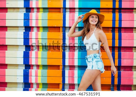 young pretty woman with hat looking over her shoulder and smiling on a colorful background in the summer time