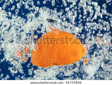 Orange (mandarin) floating in blue water with air bubbles