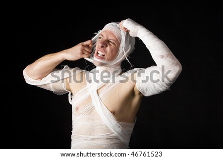 Studio image of a young man bandaged, on black background.