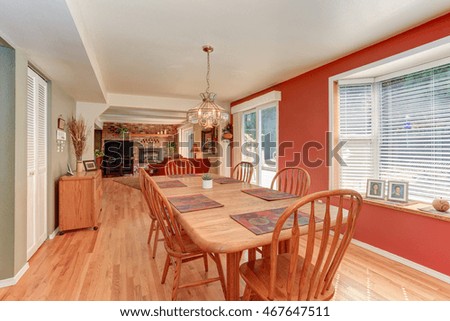 Red dining room interior with large wooden table and chairs. Connected with living room. Northwest, USA