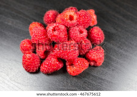 Raspberries isolated on black wooden background, selective focus, depth of field