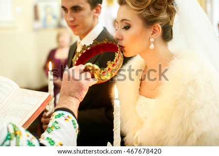 Bride kisses a golden crown held by a priest during the ceremony
