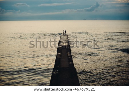Couple stands on the berth over the calm sea