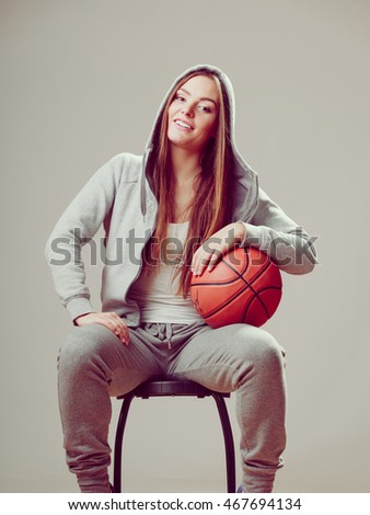 Happy sporty teenager girl wearing hooded sweatshirt holding basketball. Teen sport. 