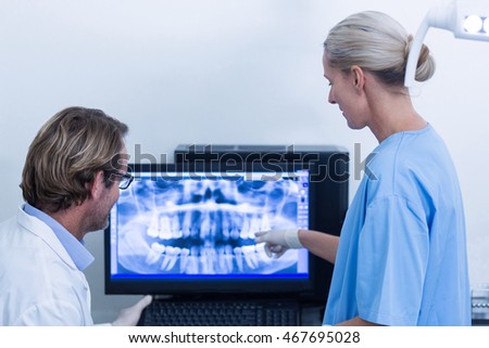 Dentist and dental assistant discussing a x-ray on the monitor in dental clinic