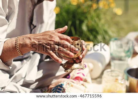 Closeupf of Indian man's hands making a turmeric pasta in steel goblet