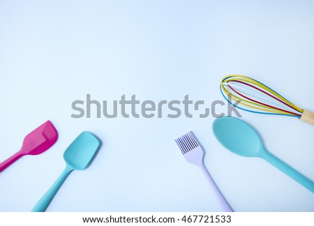 Colorful baking utensils arranged on a pastel blue background forming a page border