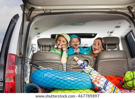Cute mom with sons peeking from behind a car seat