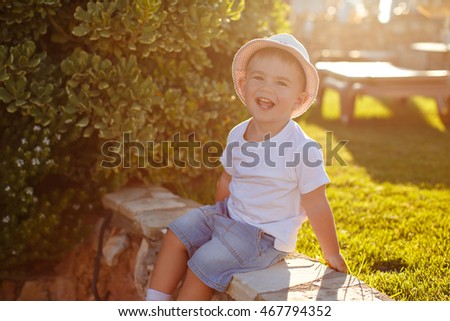 Charming boy in a hat on a background of palm trees at sunset in summer