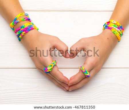 Girl give love sign. Heart gesture. Hands of little girl with rubber band wristbands show sign of love