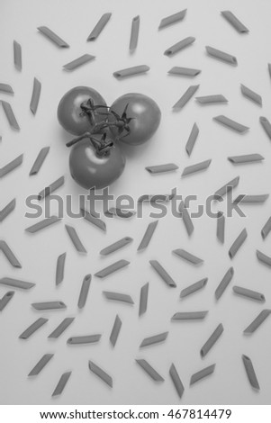 Black and white photograph of Raw pasta and fresh tomatos ingredients overhead view