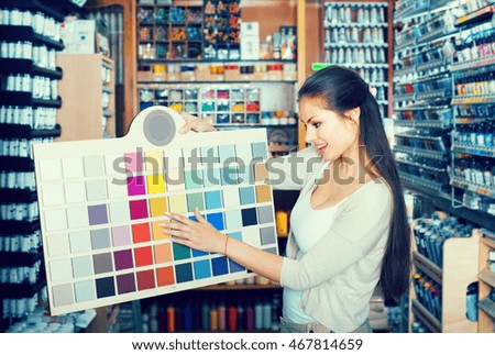 Ã¯Â»Â¿Young smiling woman choosing paint color using sample palette in art store