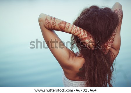 Hands with henna tattoos shake woman's hair