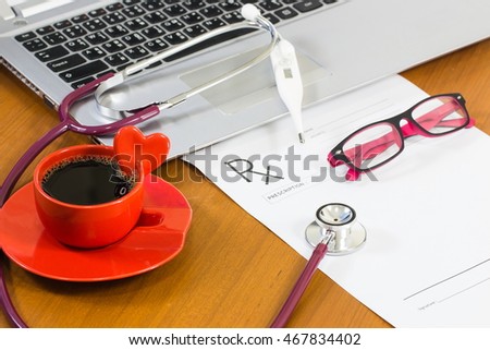 doctor workplace with a stethoscope, glasses, Thermometer, Computer and a cup of coffee on wooden table