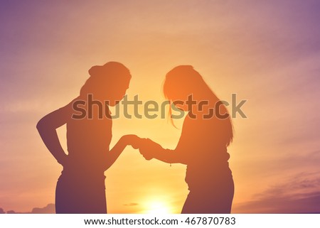 Silhouette women using smartphone on sunset