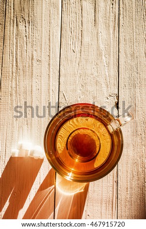Picture of glass cup with tea and sugar on wooden surface.