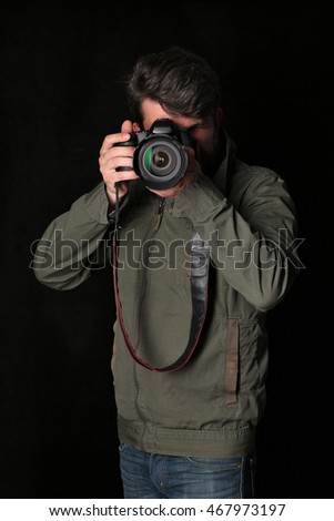 Man inkhaki jacket and jeans takes photo. Close up. Black background