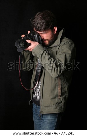 Man wearing khaki jacket takes photo. Close up. Black background