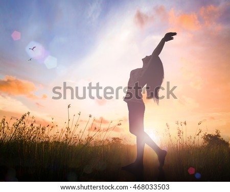 World mental health day concept: Silhouette of healthy woman raised hands for praise and worship God at autumn sunset meadow background Royalty-Free Stock Photo #468033503