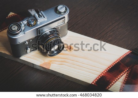 Old rangefinder camera and film on wooden board 