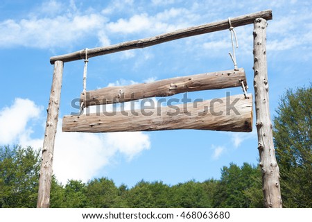Farm entrance with wooden plank sign on blue sky and green forest background, empty banner