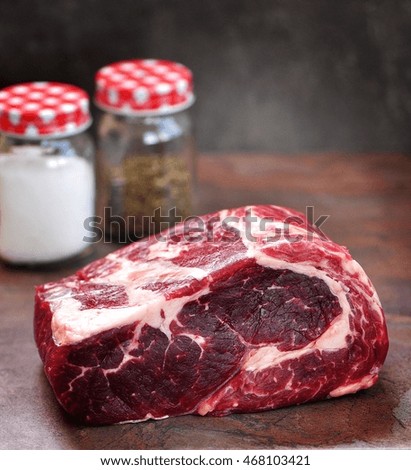 Raw ribeye steak with sea salt and dried thyme on a granite board.