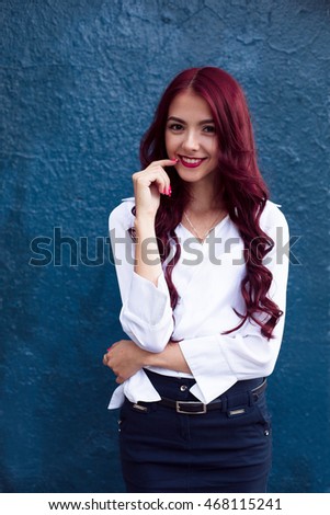 A beauty shot, photo, picture of a young, smiling, laughing, crazy, full of fun and joy dark eyed woman, girl with her red, perfect healthy skin standing on the blue background, looking at camera
