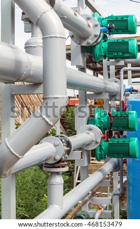 Pumps, valves and grey steel pipes at industrial boiler