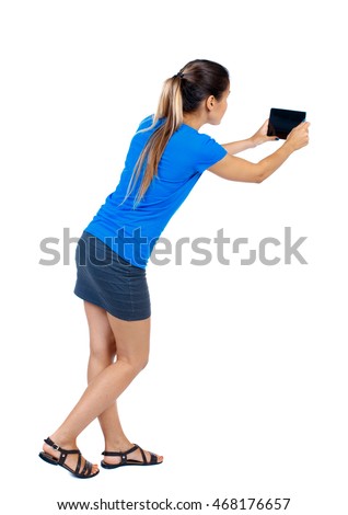 back view of standing young beautiful  woman  using a mobile phone. girl  watching. Rear view people collection.  backside view of person.  Isolated over white background. girl in a short skirt and a