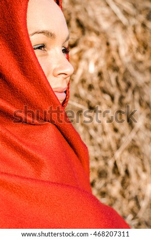 girl or woman in the countryside wrapped in a red blanket or layer