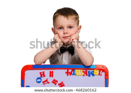 elegant little schoolboy with bowtie and board with alphabet looking at the camera isolated on white background